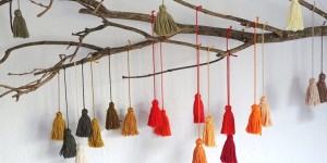 Beitragsbild des Blogbeitrags Farbenfroh: Ast mit Quasten aus Stickgarn